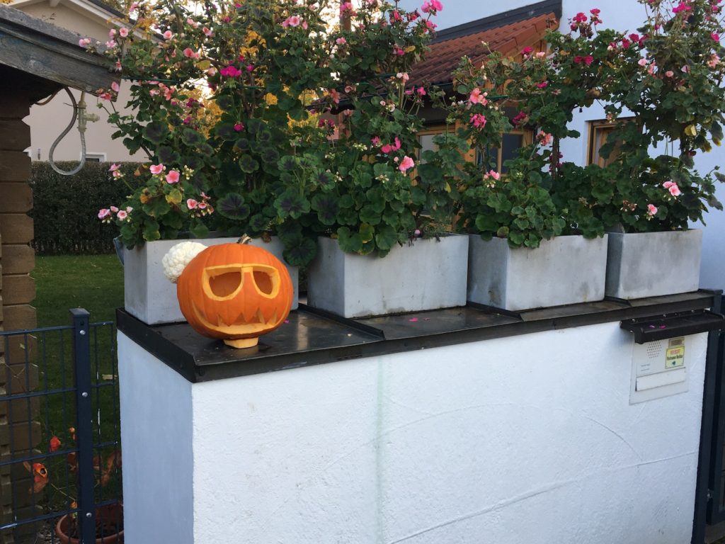 Calabaza de Halloween con gafas en la entrada de una casa